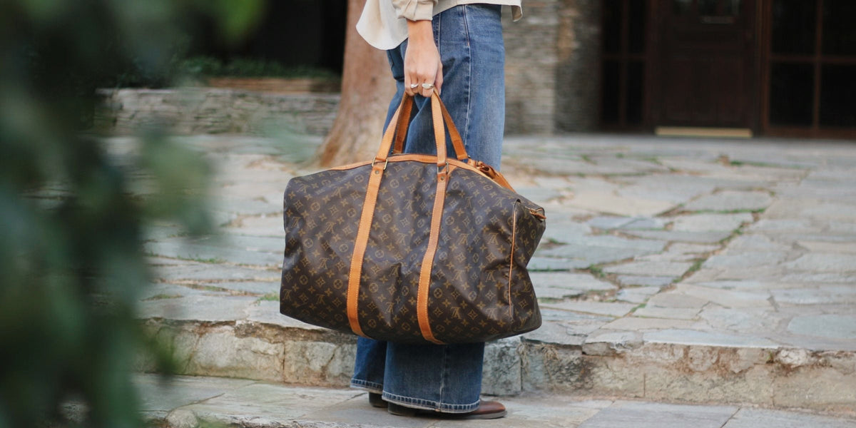 Pre-owned Louis Vuitton Keepall in Monogram canvas carried by its vachetta handles on stone steps