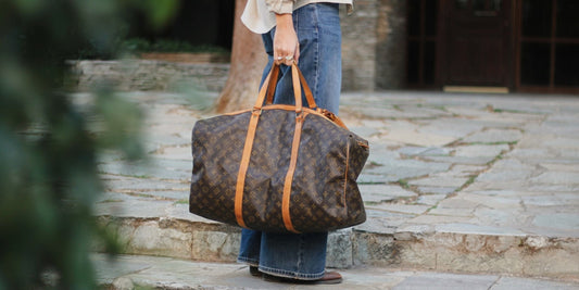 Pre-owned Louis Vuitton Keepall in Monogram canvas carried by its vachetta handles on stone steps