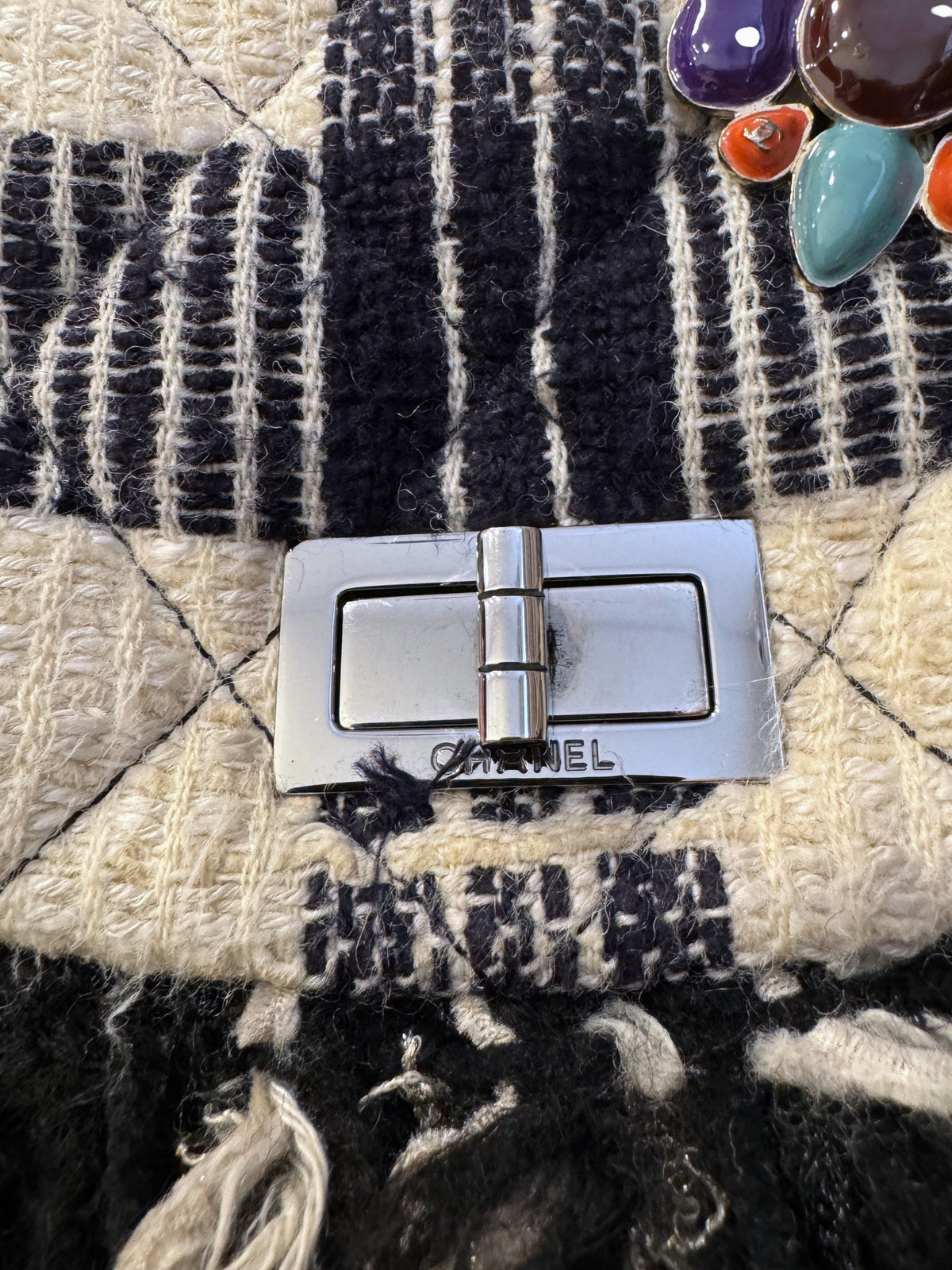 Brandsamsara vintage Chanel flap bag in multicolor tweed with fringe trim, silver turn lock, and jeweled brooch.